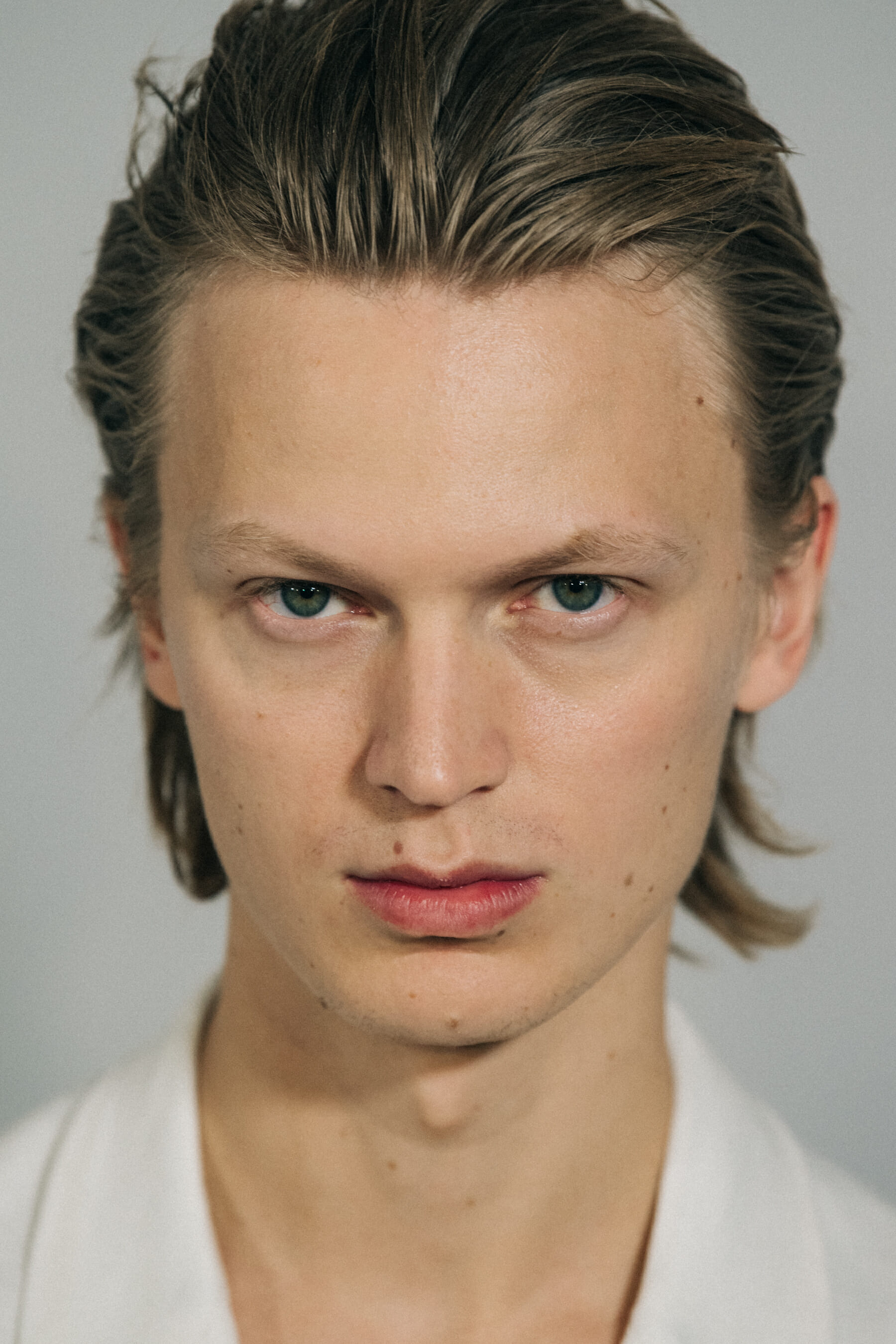 Model wearing white jacket backstage at Haider Ackermann
